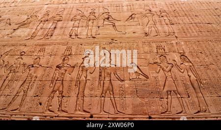 Wandkunst Bas Relief, in dem Ptolemäer V. Epiphanes dargestellt werden, die Horus und Hathor im Tempel des Horus in Edfu opferten, der während der ptolemäischen Ära zwischen 237 und 57 v. Chr. in der Nähe von Assuan, Ägypten, erbaut wurde Stockfoto