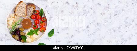 Snacks aus Käse, Oliven, Tomaten und gesalzenem Karamell. Teller mit Vorspeise oder Antipasto Stockfoto