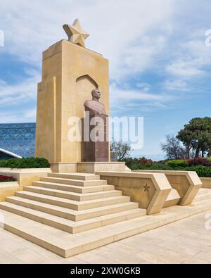 Baku, Aserbaidschan - 6. Mai 2024: Die Statue von Hazi Aslanov steht auf Steintreppen, umgeben von Grün und moderner Architektur, im Sonnenlicht Stockfoto
