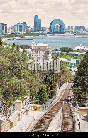 Blick auf Baku, Aserbaidschan. Im Vordergrund befindet sich die Baku-Seilbahn durch ein üppiges Grün. . Im Hintergrund erstreckt sich die Skyline der Stadt über das Kaspische Meer Stockfoto