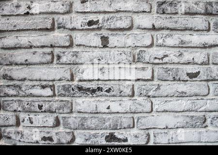 Aus nächster Nähe sehen Sie eine verwitterte graue Ziegelwand mit einzigartigen Texturen, Flecken und rustikalem Charme, perfekt für zeitgenössische Innenarchitektur und Bogen Stockfoto
