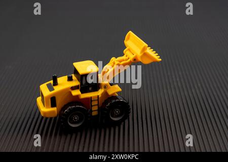 Spielzeugbagger Baumaschine auf schwarzem Hintergrund. Konstruktionskonzept. Stockfoto