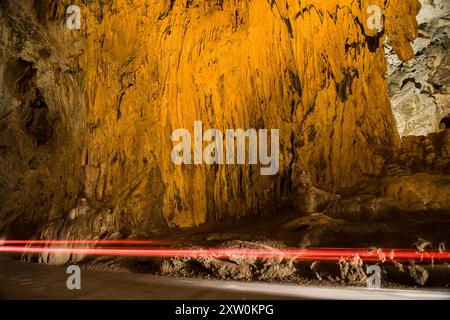 Fahrzeug, das vor einem Fließstein im natürlichen Tunnel von La Cuevona, Cuevas, Asturien, Spanien fährt. Stockfoto