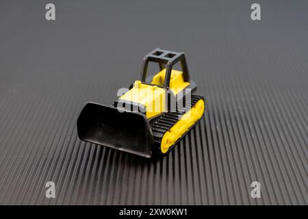 Kleiner Bulldozer auf schwarzem Hintergrund Stockfoto