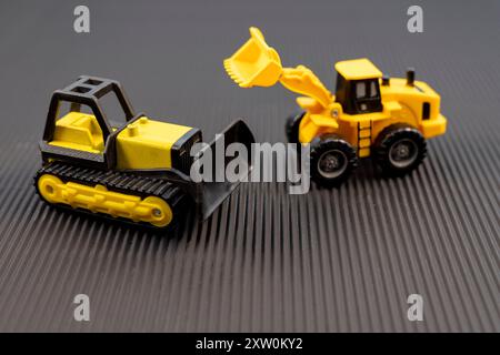 Gelbe Bauspielzeugfahrzeuge auf schwarzem Hintergrund Stockfoto