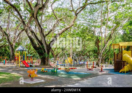 Ein Kinderspielplatz im Schatten von Bäumen im Penang Municipal Park oder Jugendpark in George Town, Penang, Malaysia Stockfoto