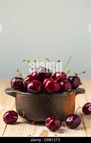 Reife Kirschen in einer Tonschale auf einem Holztisch, Nahaufnahme Stockfoto