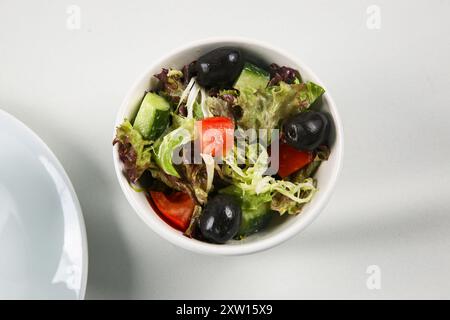 Weiße Keramikschale mit griechischem Salat auf weißem Hintergrund, frischer gemischter Salat Stockfoto