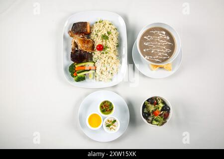Gebratener Reis mit Knoblauch und grüner Erbse mit gegrilltem Gemüse, Grillhähnchen, Grilllachs, Pilzsuppe, indischer Rita, Salatschüssel Stockfoto