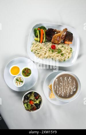 Gebratener Reis mit Knoblauch und grüner Erbse mit gegrilltem Gemüse, Grillhähnchen, Grilllachs, Pilzsuppe, indischer Rita, Salatschüssel Stockfoto