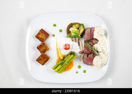 Mittelseltene Rindersteak-Medaillons mit Sauce und Spargel auf einem Teller. Köstliches gesundes Essen aus Fleisch mit Gemüse. Stockfoto