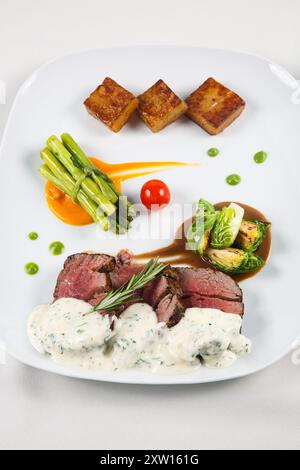 Mittelseltene Rindersteak-Medaillons mit Sauce und Spargel auf einem Teller. Köstliches gesundes Essen aus Fleisch mit Gemüse. Stockfoto