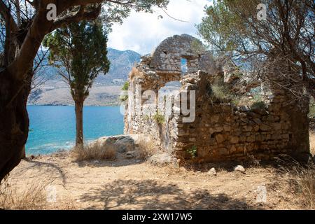 Alte Ruine aus Stein mit einem klaffenden Loch in der Wand steht mit Blick auf eine wunderschöne Bucht in griechenland Stockfoto