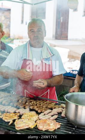 Grill Master at Work: Alter Mann, der Steaks und Kebabs zubereitet. 6. 2. 2024 Radanje Mazedonien Stockfoto