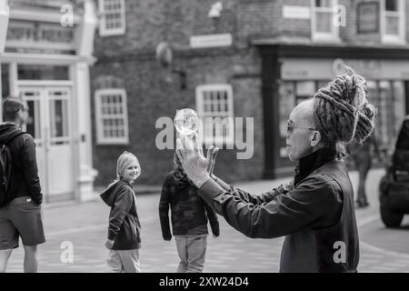 Ein erfahrener Straßenkünstler mit Dreadlocks schafft mit einer Kristallkugel faszinierende Illusionen in York, North Yorkshire, Großbritannien. Stockfoto