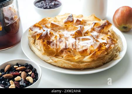 Hausgemachtes Gebäck, Apfelkuchen aus Filet-Teig, Nüsse und Tee auf einem weißen Tisch. Ausgewählter Fokus. Hochwertige Fotos Stockfoto