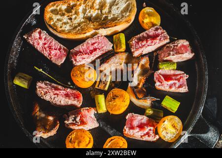 Thunfisch wird in einer gusseisernen Pfanne mit Kirschtomaten, Spargel, Speck und Toast gebraten. Hochwertige Fotos Stockfoto