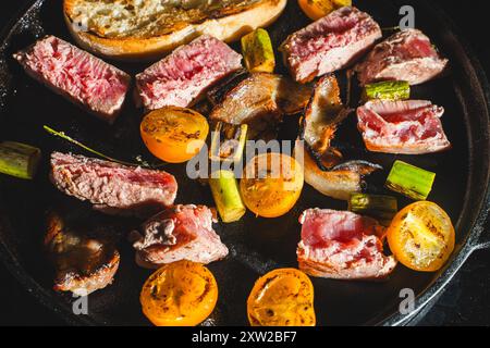 Thunfisch wird in einer gusseisernen Pfanne mit Kirschtomaten, Spargel, Speck und Toast gebraten. Hochwertige Fotos Stockfoto