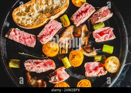 Thunfisch wird in einer gusseisernen Pfanne mit Kirschtomaten, Spargel, Speck und Toast gebraten. Hochwertige Fotos Stockfoto