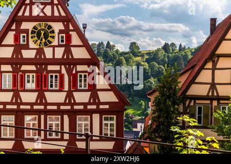 Das Rathaus von Altensteig ist ein Fachwerkgebäude aus der Mitte des 15. Jahrhunderts, erbaut im alemannischen Fachwerkstil, Kirchstraße, Baden-Württemberg, Deutschland. Ein goldenes Zifferblatt mit römischen Ziffern sitzt im Giebel, eingerahmt von rot gestrichenen Fensterläden. Stockfoto