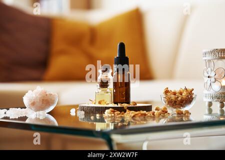 Flaschen mit ätherischem Öl mit rosafarbenem Himalaya-Meersalz und trockenen Kräutern auf einem Tisch im Wohnzimmer Stockfoto