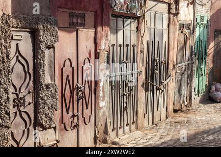 Anordnung geschlossener Eisentüren zum Schutz der Geschäfte in einer Gasse in der Medina von Marrakesch Stockfoto