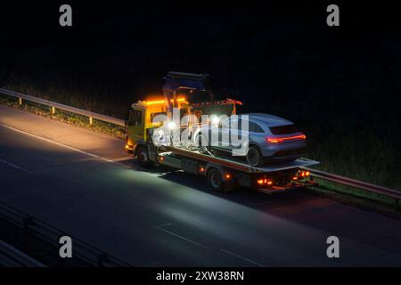 Autorettung transportiert einen belasteten Luxuswagen, der während der Arbeiten auf einer Autobahn abschleppt Stockfoto