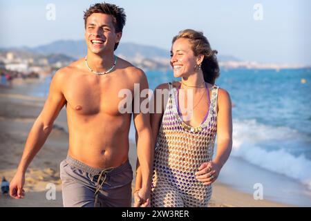 Glückliches Paar, das Hände hält und auf das Meer blickt Stockfoto