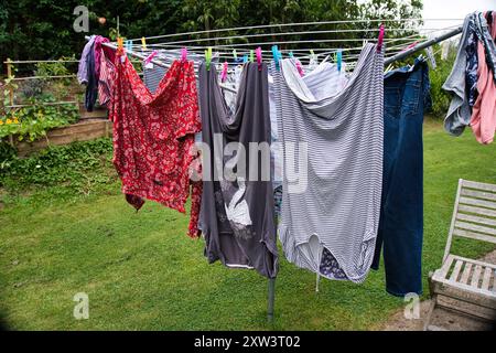 Kleidung hängt zum Trocknen auf einem drehbaren Wäschetrockner im Garten Stockfoto