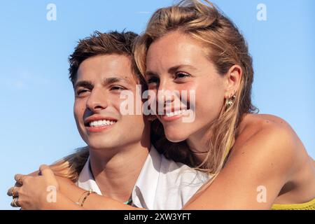 Glückliches Paar, Das Sich Umarmt Und Am Strand Sitzt Und Auf Das Meer Blickt Stockfoto
