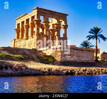 Wunderschöner Blick auf den Kiosk von Trajan bei hellblauem Himmel auf der Insel Philae mit dem Tempel der Isis auf Philae Island am Lake Nasser, erbaut von Nectanebo und Ptolemäus Pharoahs in der Nähe von Assuan, Ägypten Stockfoto