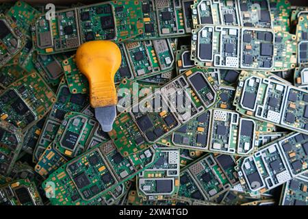 Ein Stapel Elektroschrott in der Fabrikhalle ist eine Leiterplatte des Mobiltelefons, die darauf wartet, verarbeitet zu werden, extrahiert Gold, um Edelmetall von Elektr zu trennen Stockfoto