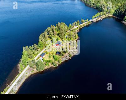 Einzelnes rotes Haus auf der Insel Kjeoeya im Kilefjorden-See, Insel mit dem Festland verbunden, Setesdal Valley, Norwegen Stockfoto