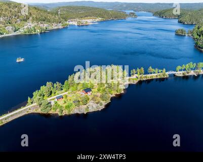 Einzelnes rotes Haus auf der Insel Kjeoeya im Kilefjorden-See, Insel mit dem Festland verbunden, Setesdal Valley, Norwegen Stockfoto