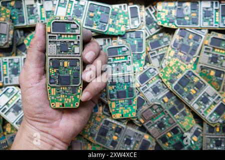 Ein Stapel Elektroschrott in der Fabrikhalle ist eine Leiterplatte des Mobiltelefons, die darauf wartet, verarbeitet zu werden, extrahiert Gold, um Edelmetall von Elektr zu trennen Stockfoto