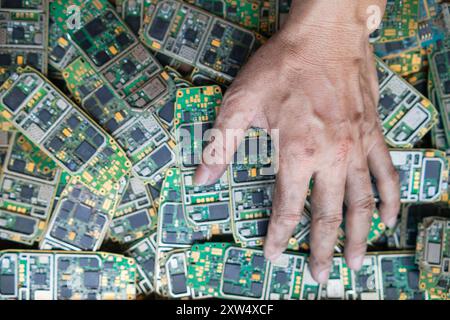 Ein Stapel Elektroschrott in der Fabrikhalle ist eine Leiterplatte des Mobiltelefons, die darauf wartet, verarbeitet zu werden, extrahiert Gold, um Edelmetall von Elektr zu trennen Stockfoto