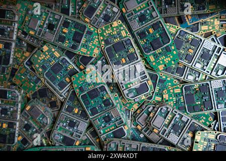 Ein Stapel Elektroschrott in der Fabrikhalle ist eine Leiterplatte des Mobiltelefons, die darauf wartet, verarbeitet zu werden, extrahiert Gold, um Edelmetall von Elektr zu trennen Stockfoto