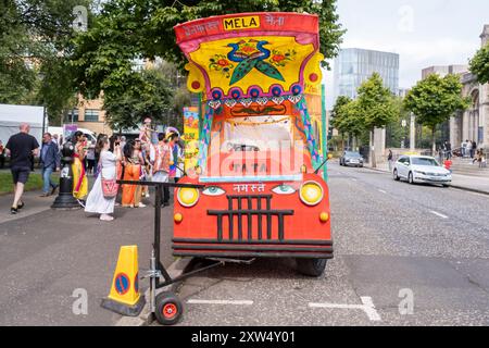 Belfast Mela Carnival Parade: Farbenfroher rot-gelber und orangener Wagen mit indischen Kulturdarstellungen. Belfast, Großbritannien - 17. August 2024. Stockfoto