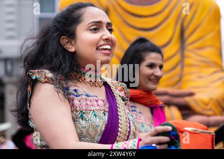 Belfast Mela Carnival Parade - eine junge Asiatin im wunderschönen Kostüm im indischen Stil lächelt vor süßer Begeisterung. Belfast, Großbritannien - 17. August 2024. Stockfoto