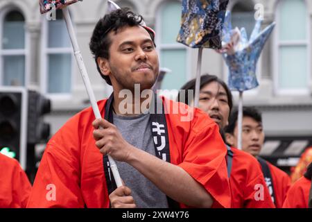 Belfast Mela multikulturelle Karnevalsparade - Gruppe, Männer in Rot und Schwarz, die mit der Japan Society of Northern Ireland paraden. Belfast, Großbritannien - 17. August 2024. Stockfoto