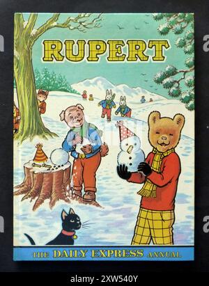 Ein Jahrgang „Rupert“ für Kinder, der 1974 von der Tageszeitung Daily Express veröffentlicht wurde. Das jährliche Jahr basiert auf der beliebten englischen Comicfigur Rupert Bear, die 1920 erstmals im Daily Express erschien. Das farbenfrohe Cover zeigt Rupert, der mit seinem Freund Algy Pug Schneemänner baut. Außerdem sind Reggie und Rex Rabbit sowie Freddy und Ferdie Fox zu sehen. Stockfoto