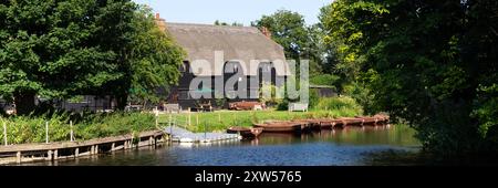 EAST BERGHOLT, SUFFOLK, Großbritannien - 29. JULI 2024: Panoramablick auf den Teesaal Flatford Mill über den Fluss Stour Stockfoto