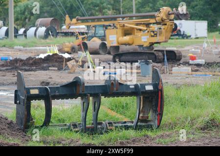 Weitsicht-Schotterhaufen links zur elektrischen Umspannstation für Baumaschinen mit Hochspannungsleitungen in St. Petersburg, Florida. Blick auf das grüne Gras Stockfoto