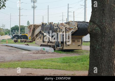 Weitsicht-Schotterhaufen links zur elektrischen Umspannstation für Baumaschinen mit Hochspannungsleitungen in St. Petersburg, Florida. Blick auf das grüne Gras Stockfoto