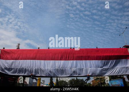 Bandung, Indonesien. August 2024. Feuerwehrleute steigen von einer Brücke ab, um während eines dreiminütigen Grußes zum 79. Unabhängigkeitstag der Republik Indonesien in Bandung, West-Java, eine riesige rot-weiße Flagge zu heben. (Foto: Dimas Rachmatsyah/Pacific Press) Credit: Pacific Press Media Production Corp./Alamy Live News Stockfoto