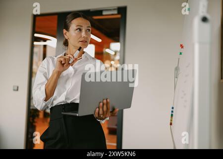 Professionelles weibliches Individuum präsentiert sich mit ihrem Laptop in einem modernen Büroumfeld Stockfoto