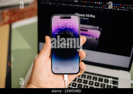 Paris, Frankreich - 29. September 2022: POV einer männlichen Hand, die das neueste iPhone 15 Pro hält, wobei die Apple Website im Hintergrund sichtbar ist und das elegante Design und die moderne Technologie des Smartphones unterstreicht Stockfoto