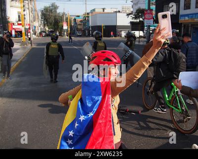 Lima, Peru. August 2024. Frau, die in die venezolanische Flagge gewickelt war, als Hunderte Venezolaner, die auf einen weltweiten Aufruf von Corina Machado antworteten, erneut auf die Straßen von Lima gingen, mit Fahnen und Spruchbändern, um gegen Nicolas Maduro und den Wahlbetrug in Venezuela zu protestieren. Venezuela brach kürzlich die diplomatischen Beziehungen zu Peru, als dieses sich weigerte, Madurros Sieg anzuerkennen. Quelle: Fotoholica Presseagentur/Alamy Live News Stockfoto