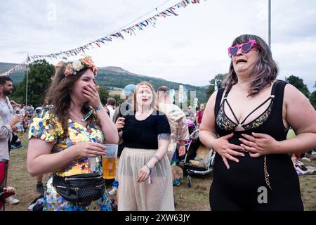GREEN MAN FESTIVAL, BRECON, WALES, Vereinigtes Königreich - 17. AUGUST 2024: Eine Gruppe von Frauen lacht und tanzt vor der Far Out Stage mit den Bergen als Kulisse. Tag des Green man Festivals 2024 im Glanusk Park, Brecon, Wales. Quelle: Rob Watkins/Alamy Live News Stockfoto