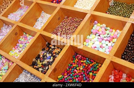 Verschiedene Farben und Formen von Perlen in Holzfächern für Heimwerkerzubehör Stockfoto